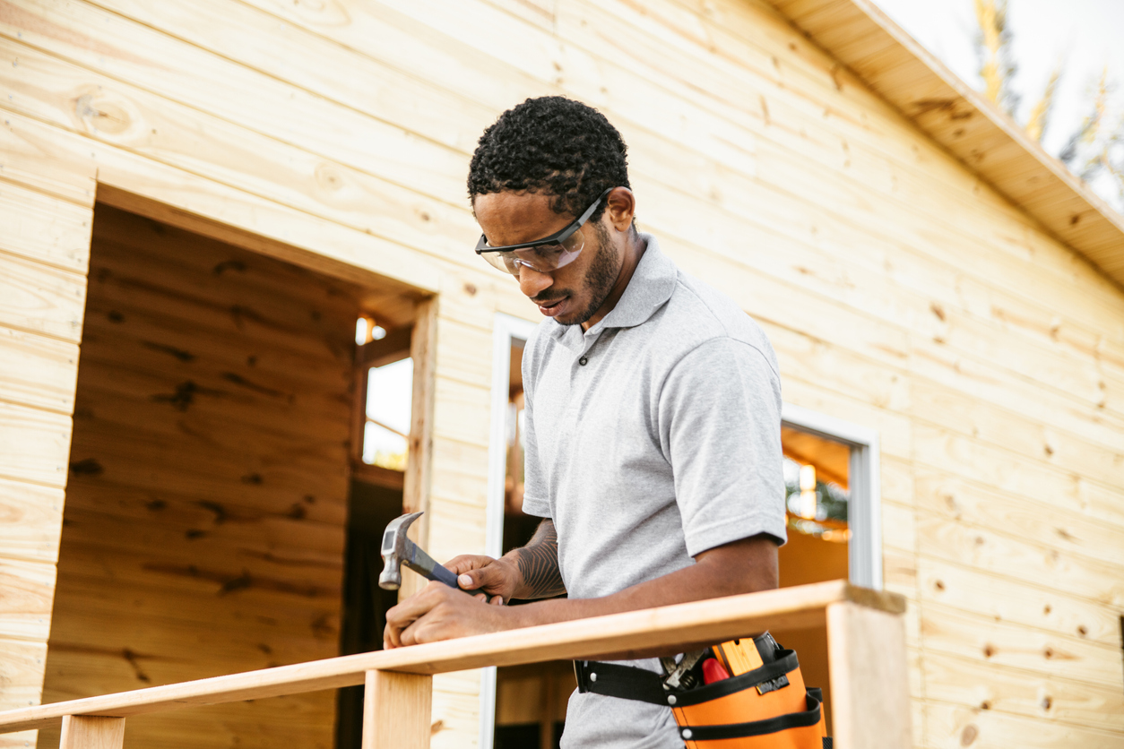 Construction worker nailing porch railing