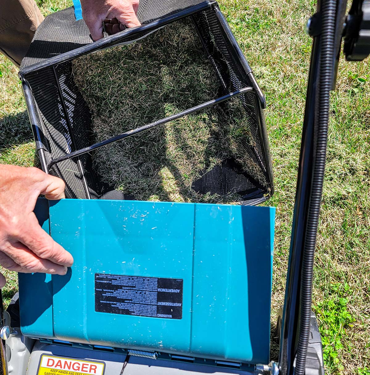 Man emptying the grass clippings from Makita lawn mower bag