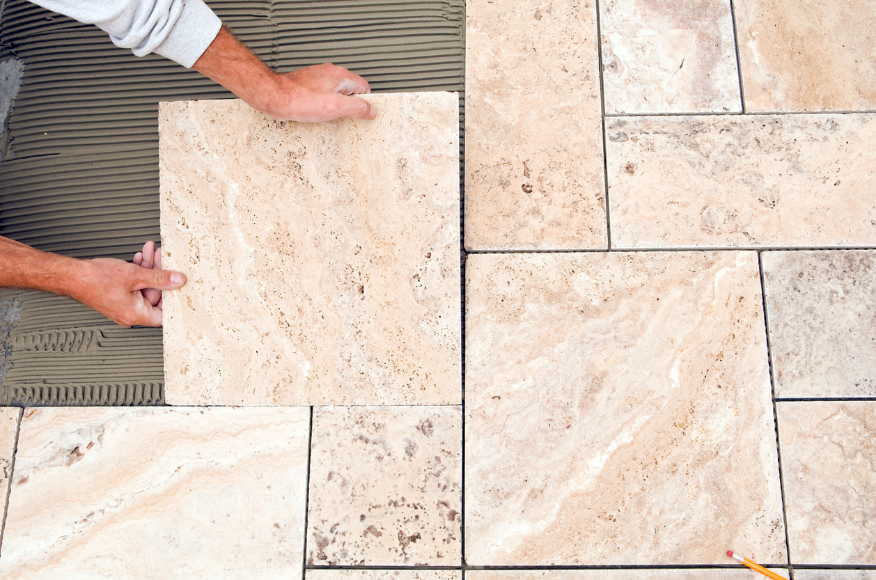 Natural stone tile flooring being installed in a bathroom