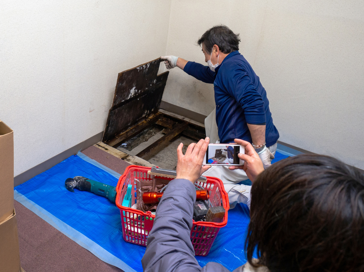 Foreman taking a picture while construction worker removing the floor.