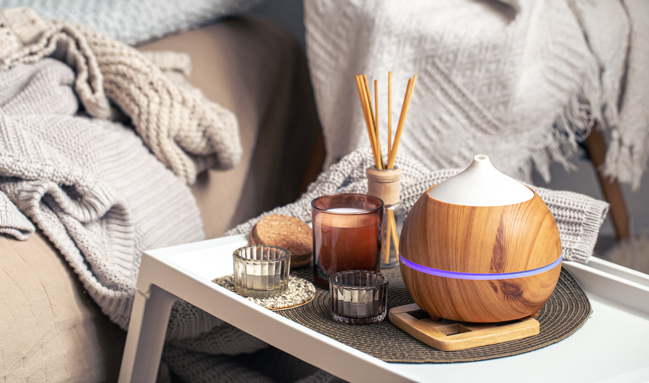 Oil diffuser on blurred background near candles.