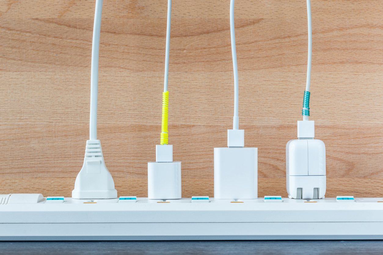 white usb cords and laptop chargers plugged into a power strip