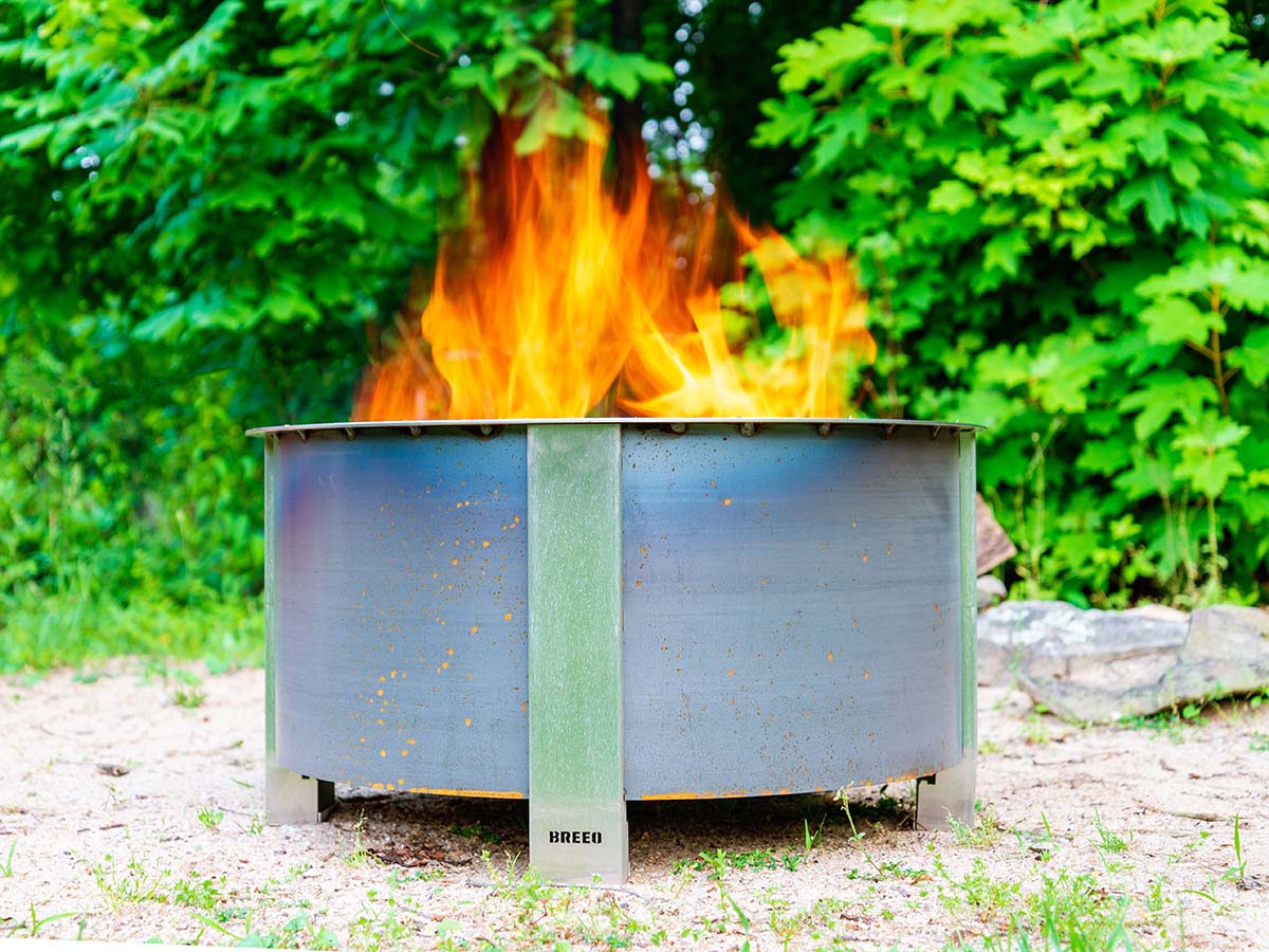 The Breeo fire pit burning an inviting fire in a wooded backyard setting