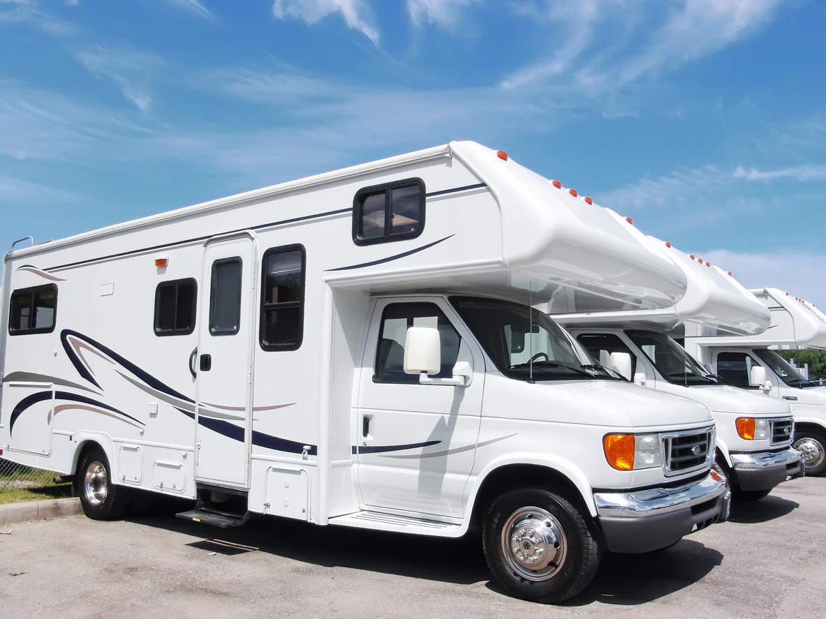 A row of RVs is parked on a clear blue day.