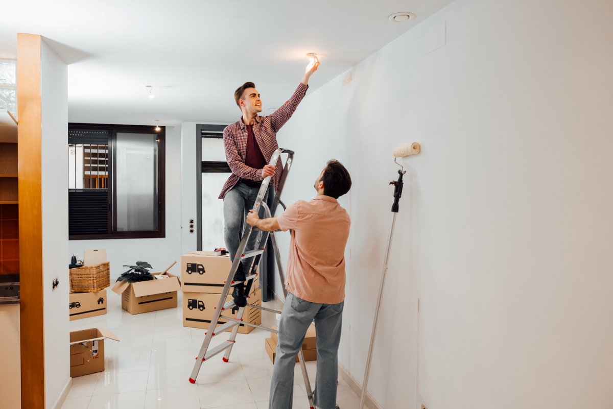 Two people using ladder to replace lightbulb