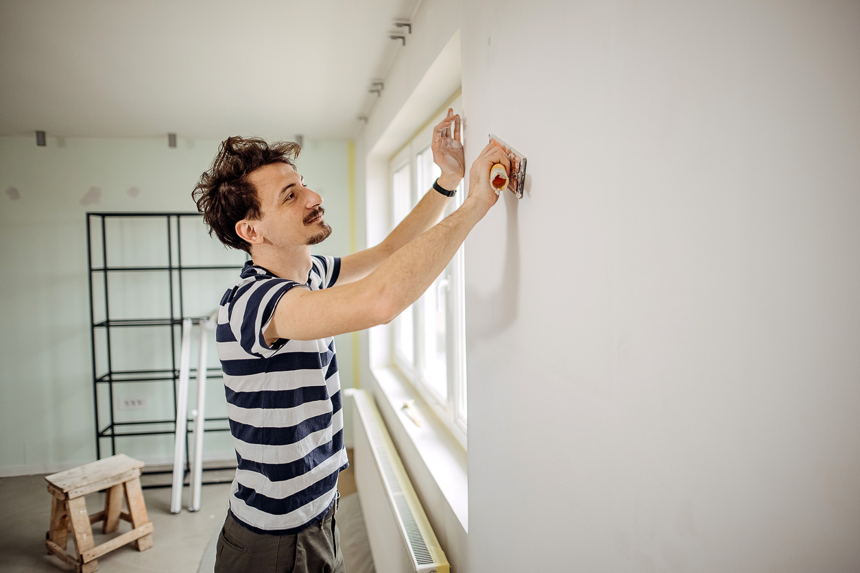 Man is preparing the wall for the painting.