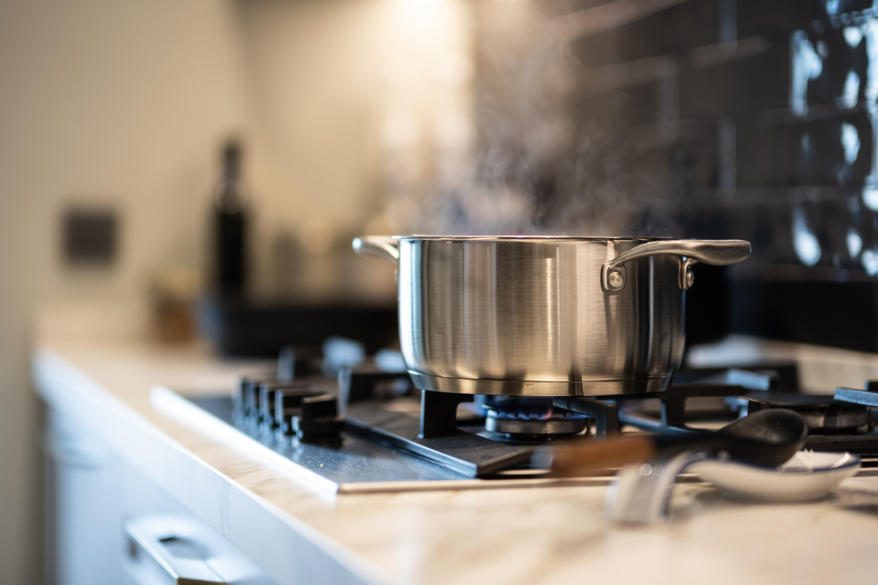 a large metal pot on stove with water boiling inside