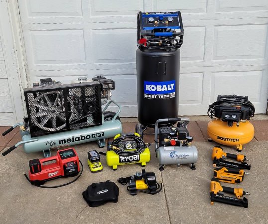 A group of the best home air compressors in front of a garage door before testing.