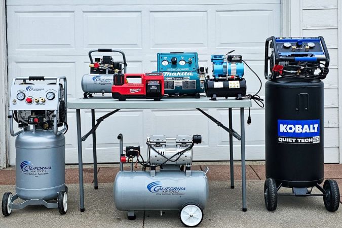A group of the best quiet air compressors in front of a garage door before testing.