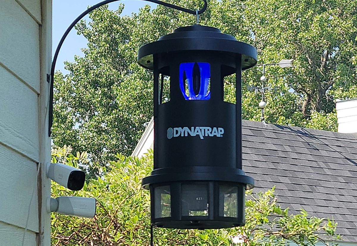 The DynaTrap insect trap hanging from a shepherd's hook off the side of a house