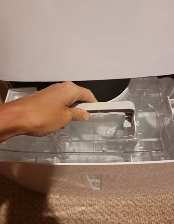 Woman pulling water tank out of Frigidaire dehumidifier