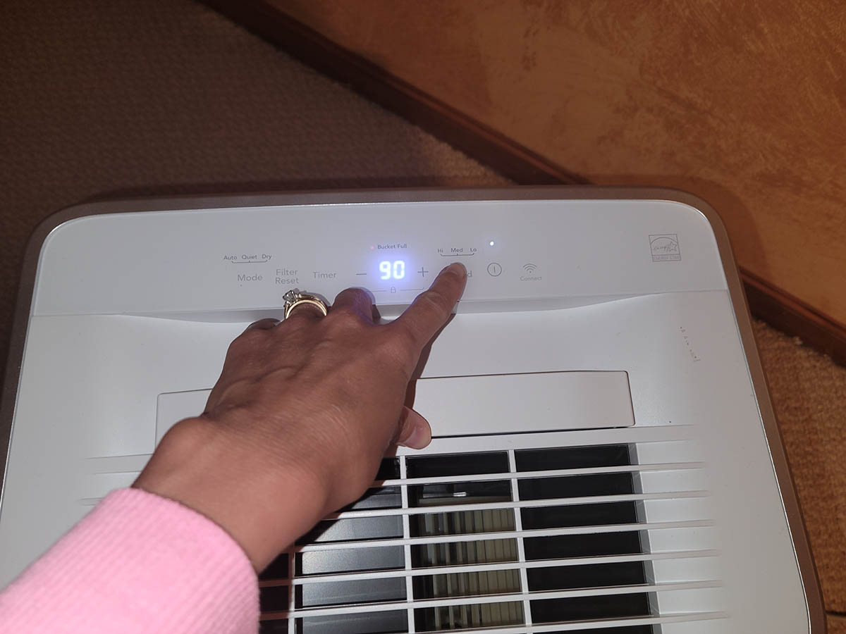 Woman pushing start button on Frigidaire Dehumidifier