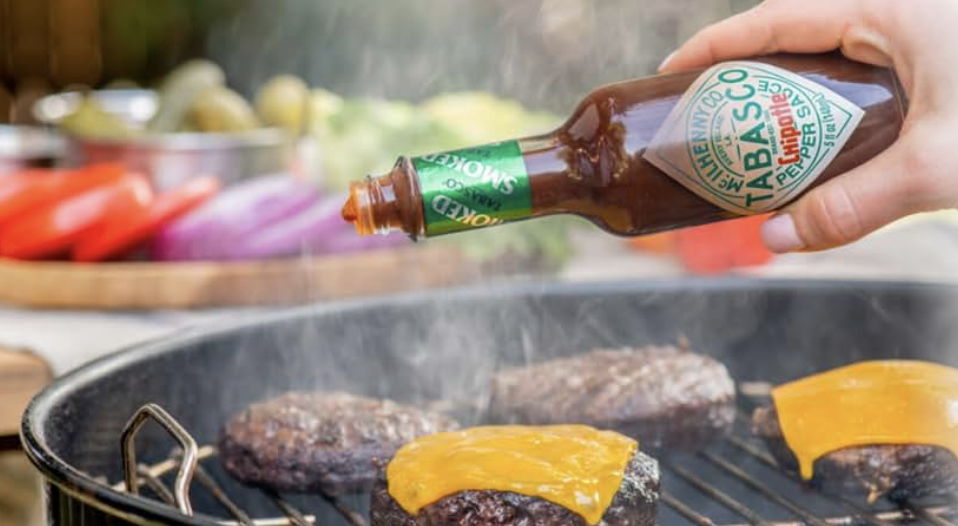 Tabasco sauce being poured on a burger