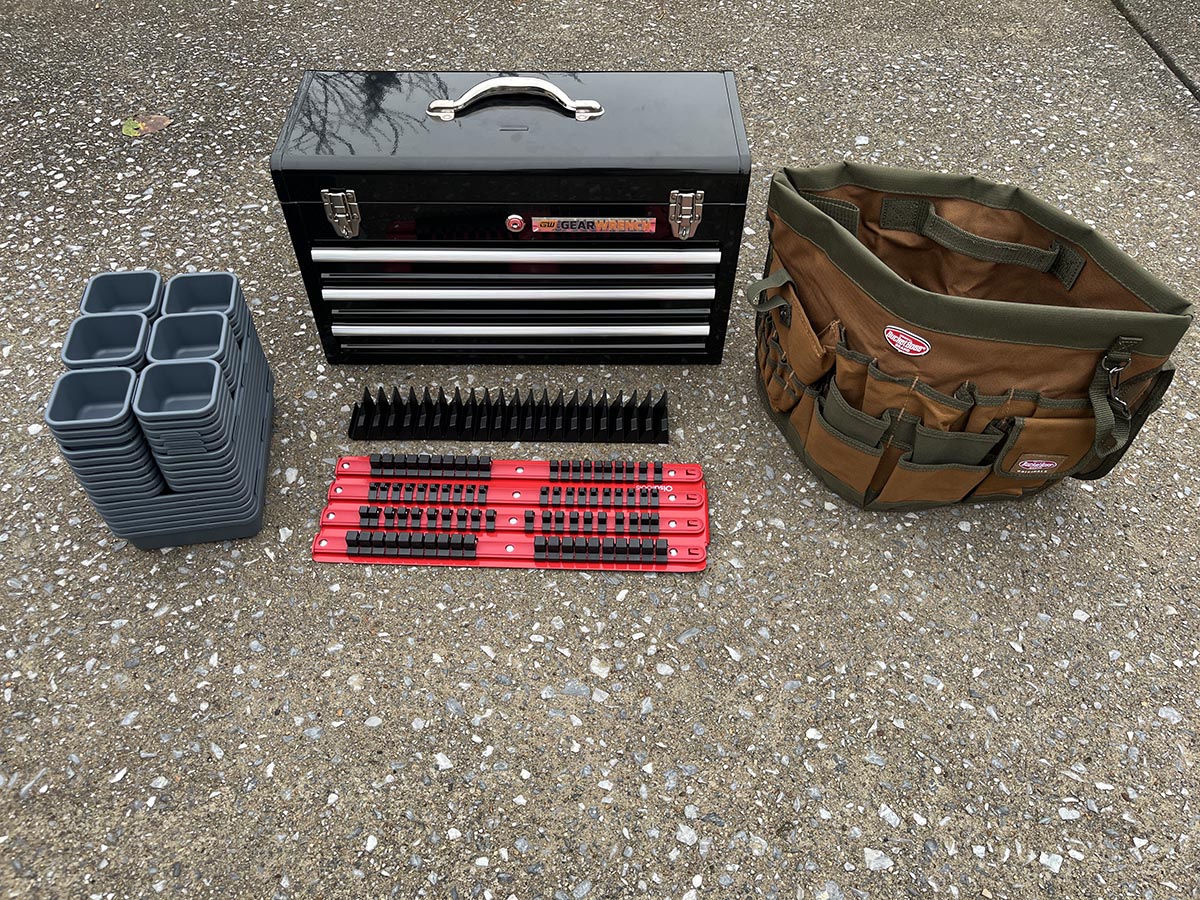 A tool box, tool buck, wrench organizer, tool organizer trays, and a socket organizer on a driveway