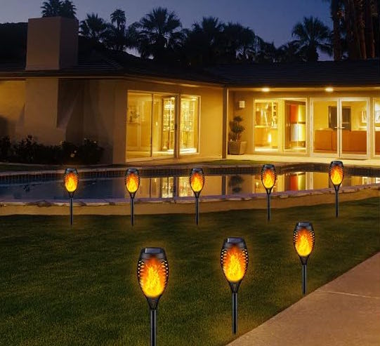 house lit up at night with torch lights in front lawn path