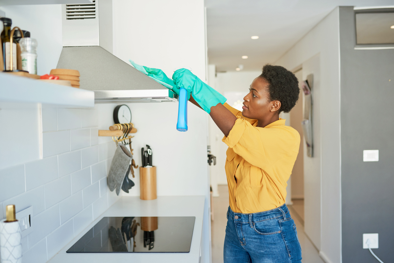 woman-cleans-a-range-hood-in-a-white-kitchen