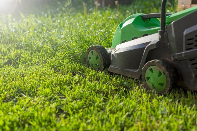 green lawnmower angled on green grass