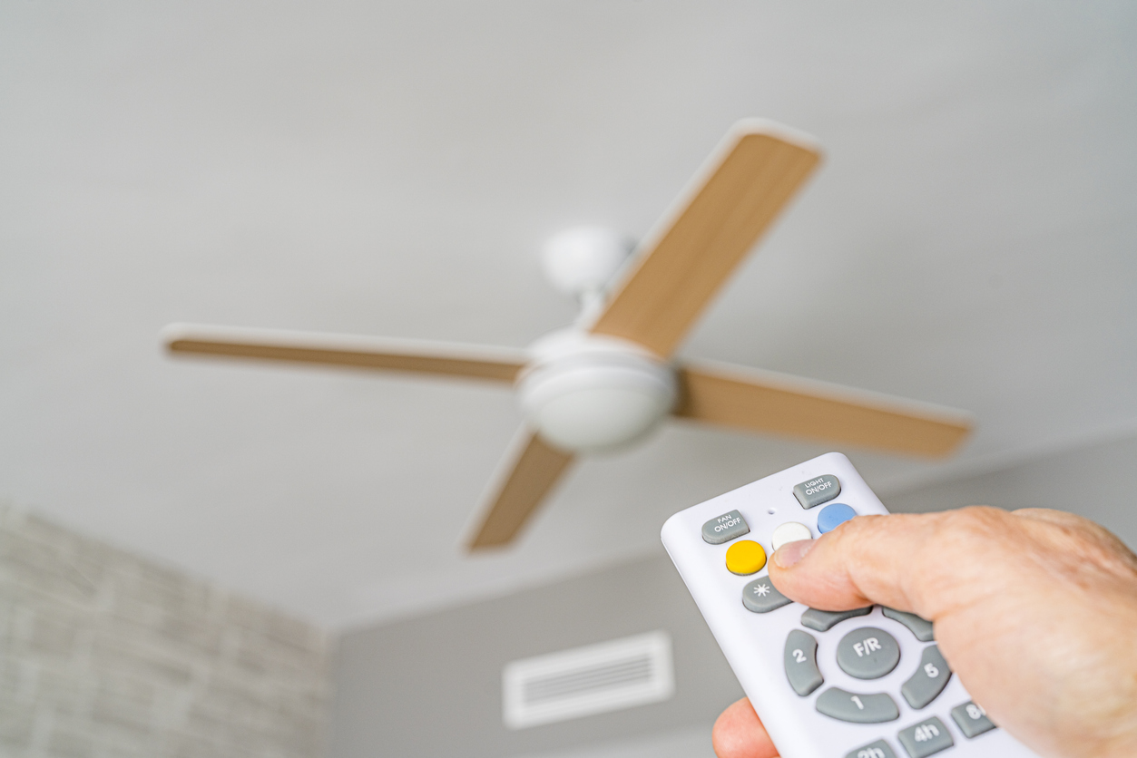 Close up of a hand holding a remote control aiming to ceiling fan. High resolution 42Mp indoors digital capture taken with SONY A7rII and Zeiss Batis 40mm F2.0 CF lens