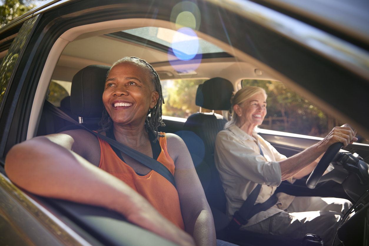 Two Senior Female Friends Enjoying Day Trip Out Driving In Car Together stock photo