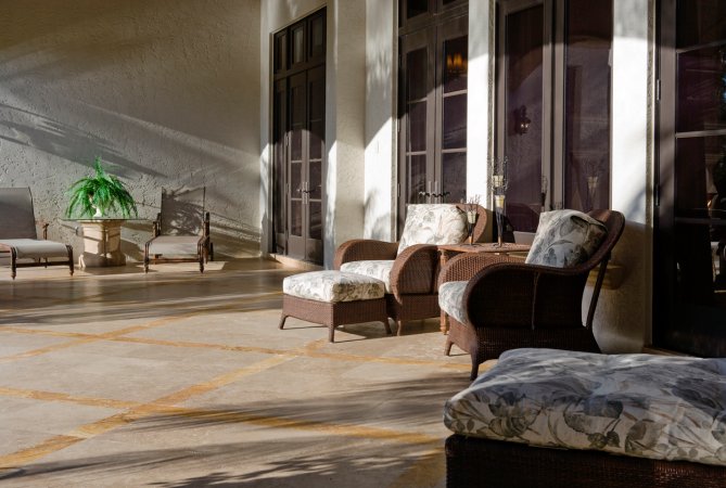 large patio with marble floor with sun shining on patio furniture