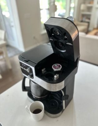 The Cuisinart Coffee Center Barista Bar 4-in-1 Coffeemaker open to show a coffee pod before brewing