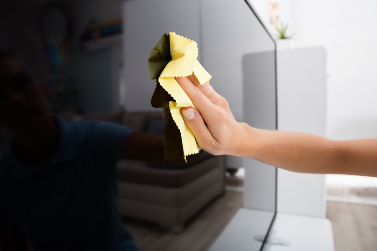 Close view of hand wiping a TV screen with a microfiber cloth