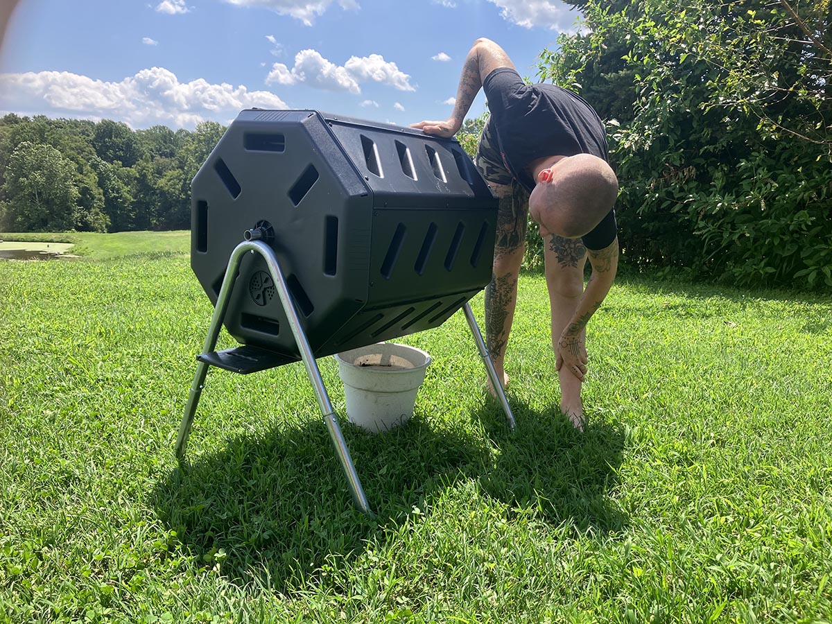 A person emptying compost from the FCMP Outdoor tumbling composter