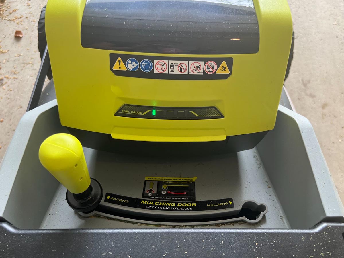 A closeup of the Ryobi 21-inch self-propelled all-wheel-drive mower's battery gauge and mulching lever