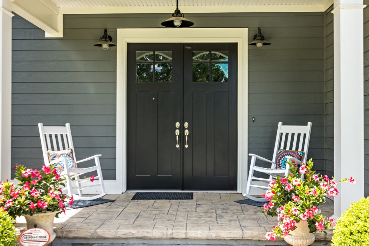 Stamped concrete patio installed to look like stone pavers on a porch with a black front door