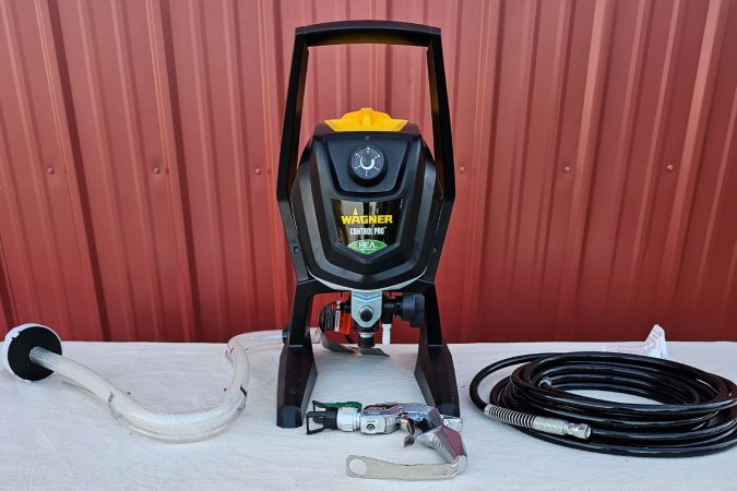 The Wagner Paint Sprayer set up next to a barn alongside all its accessories