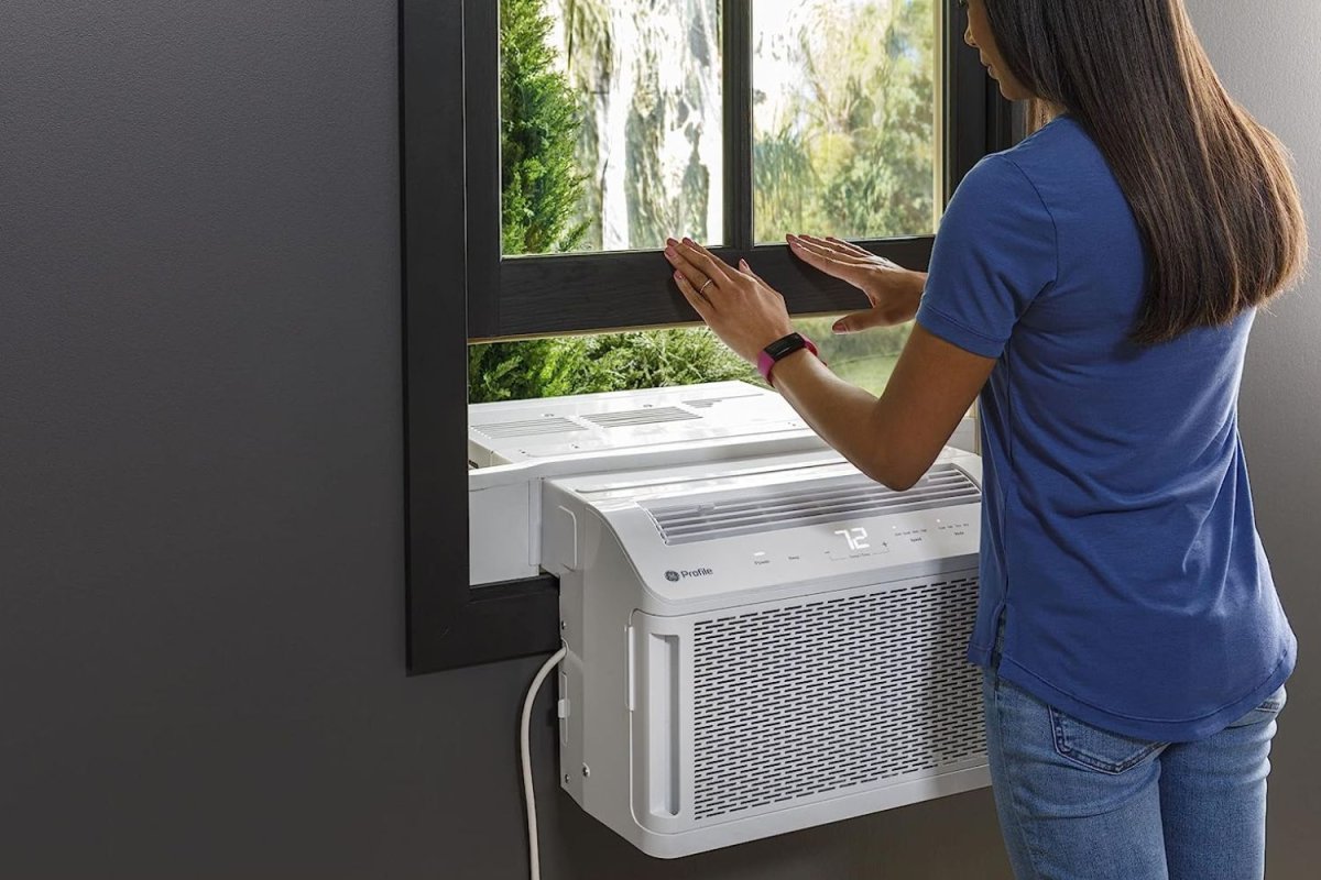 A person closing a window where the best U-shaped air conditioner option is installed