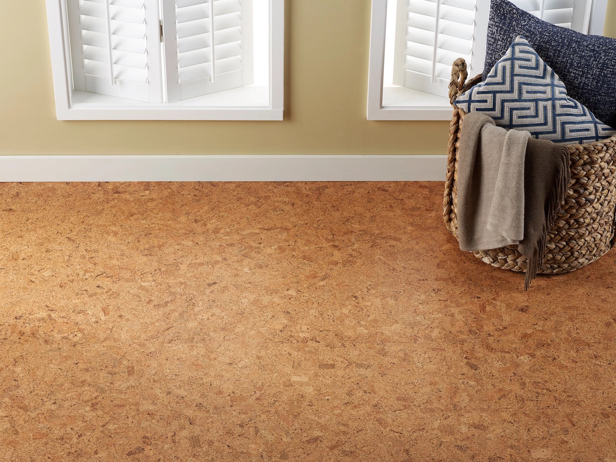 A brown cork floor with a laundry bin in frame; a beige wall with windows in the background.