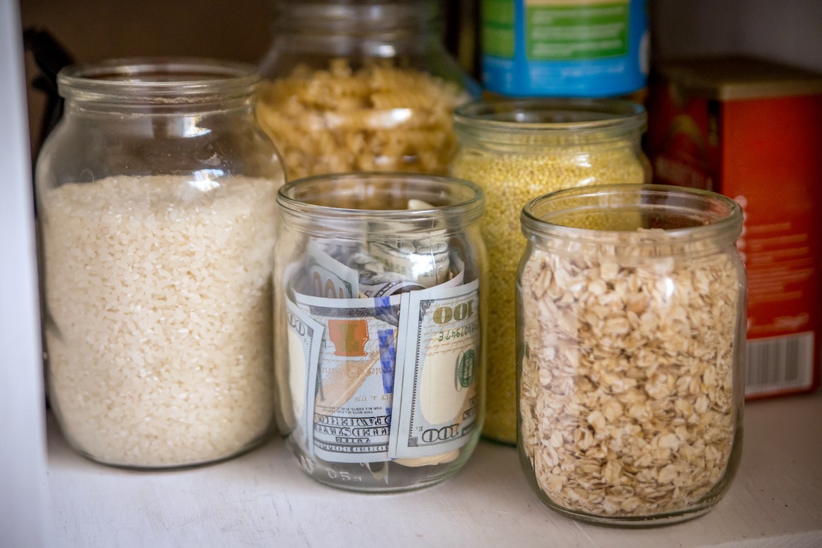Hidden money in glass jar next to jarred rice and oats in pantry.