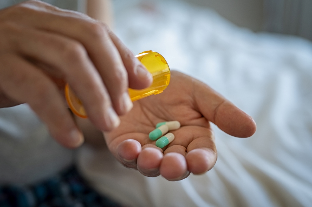 Person putting pills in hand