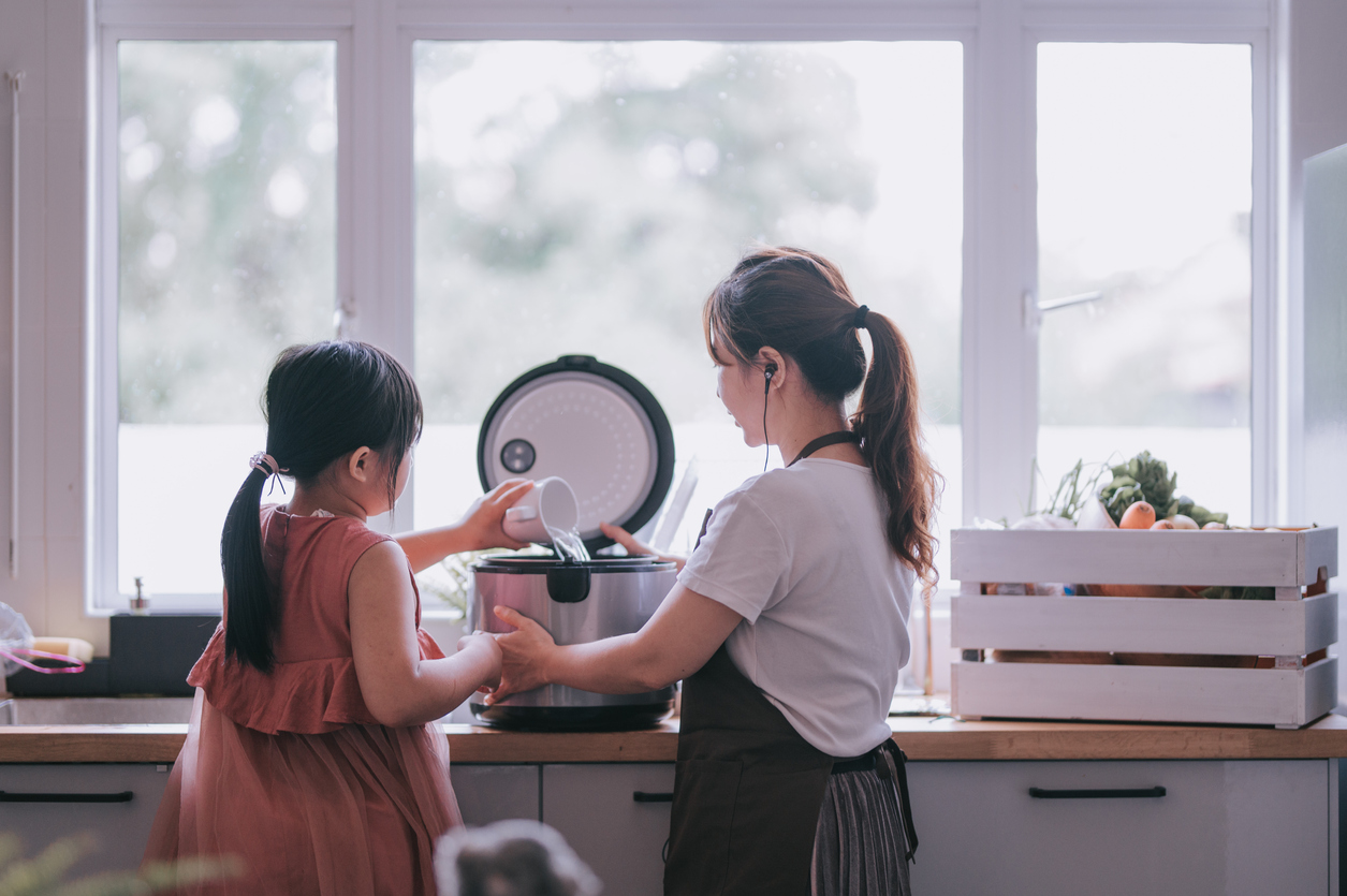 mother and daughter using rice cooker in the kitchen