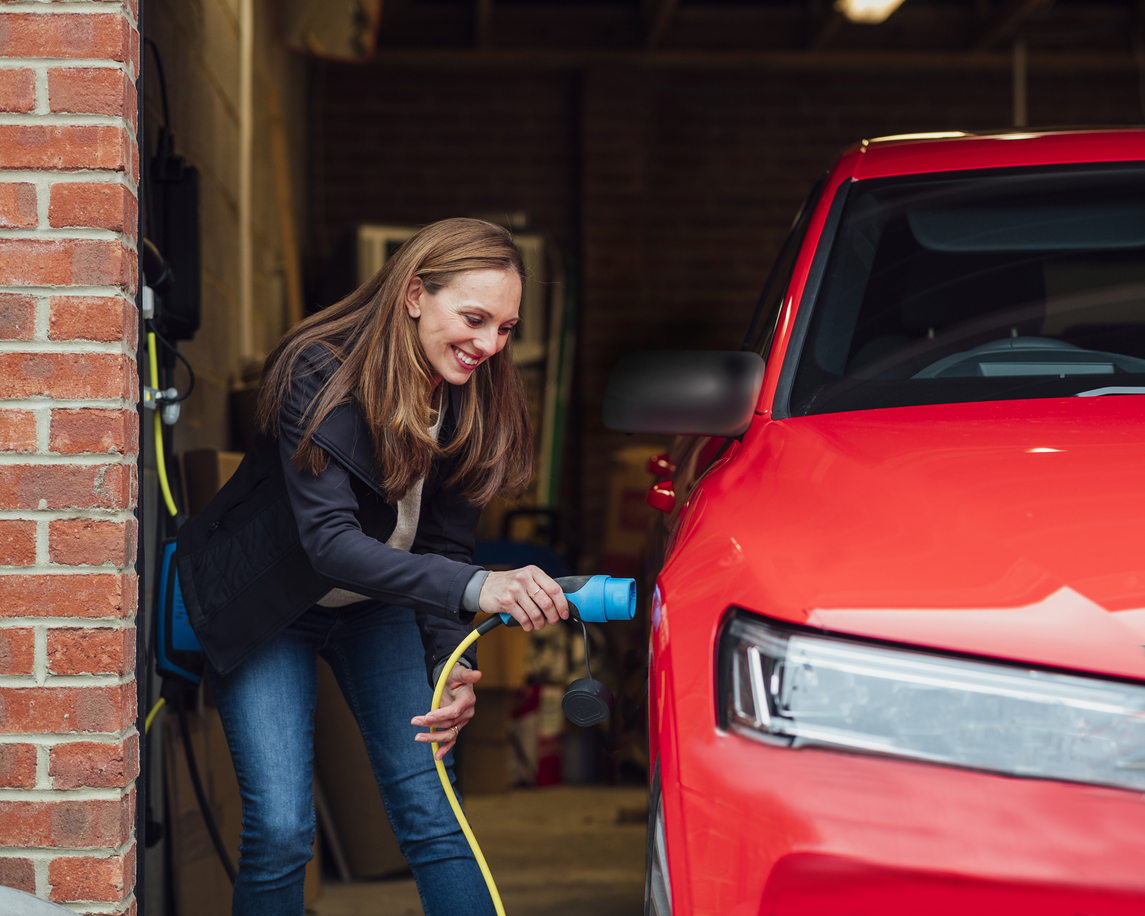 woman charging red electric car