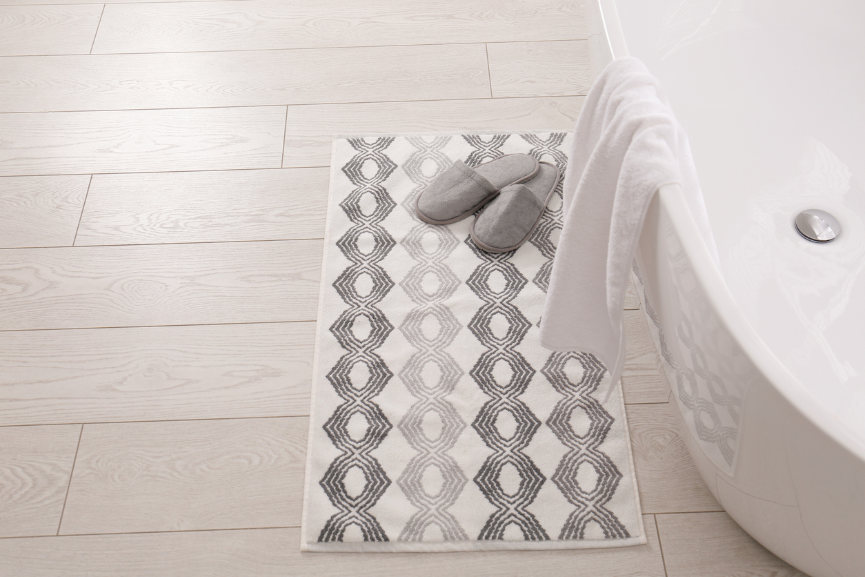 high angle view of a white and grey bath mat next to a bath tub