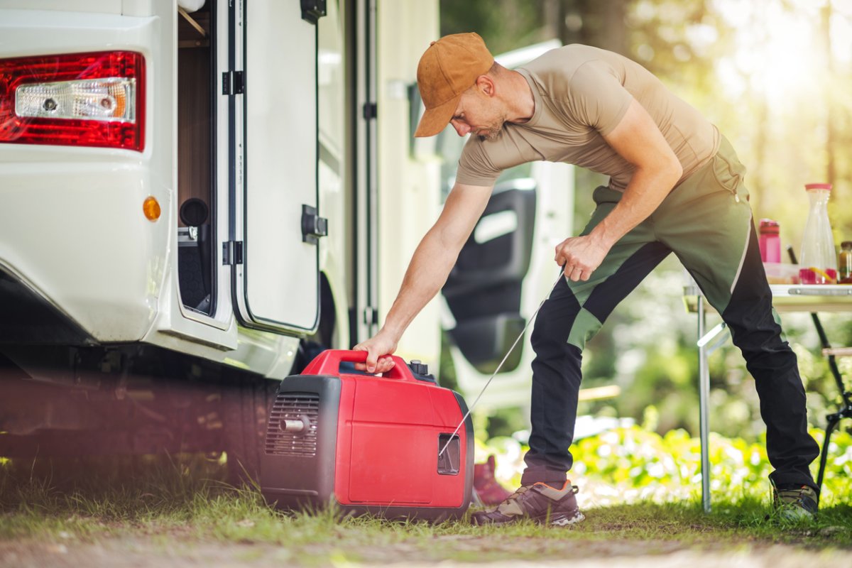 man using a portable generator on a camp ground