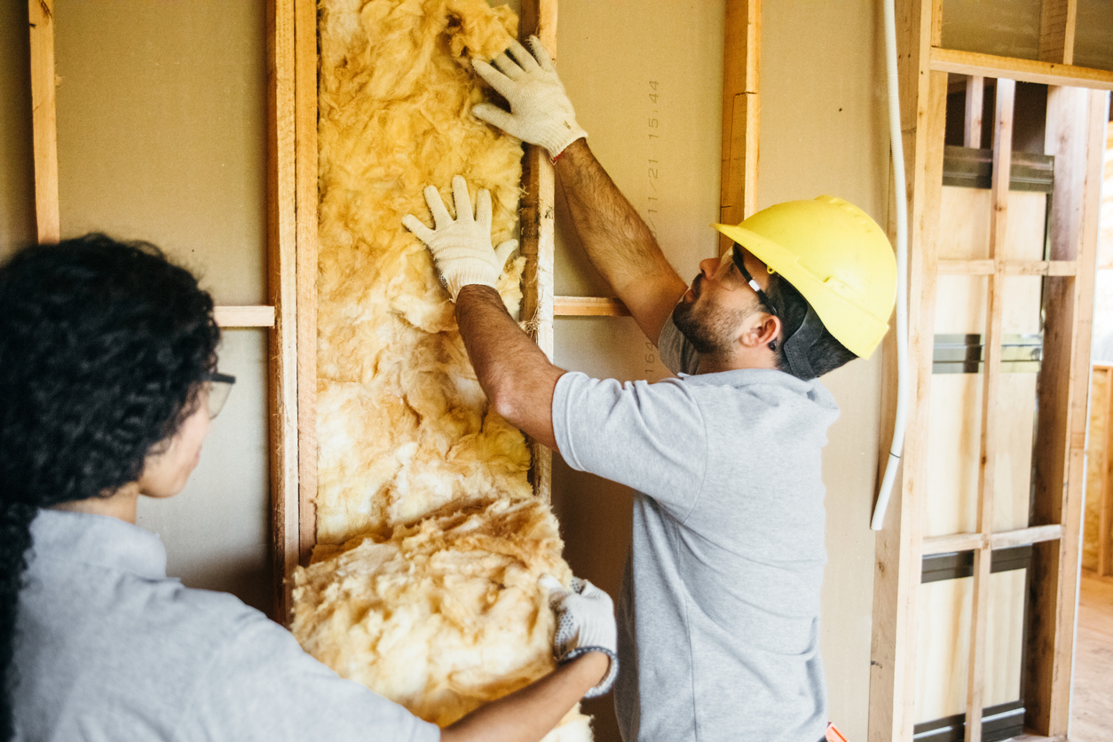 workers installing insulation in wall in attic