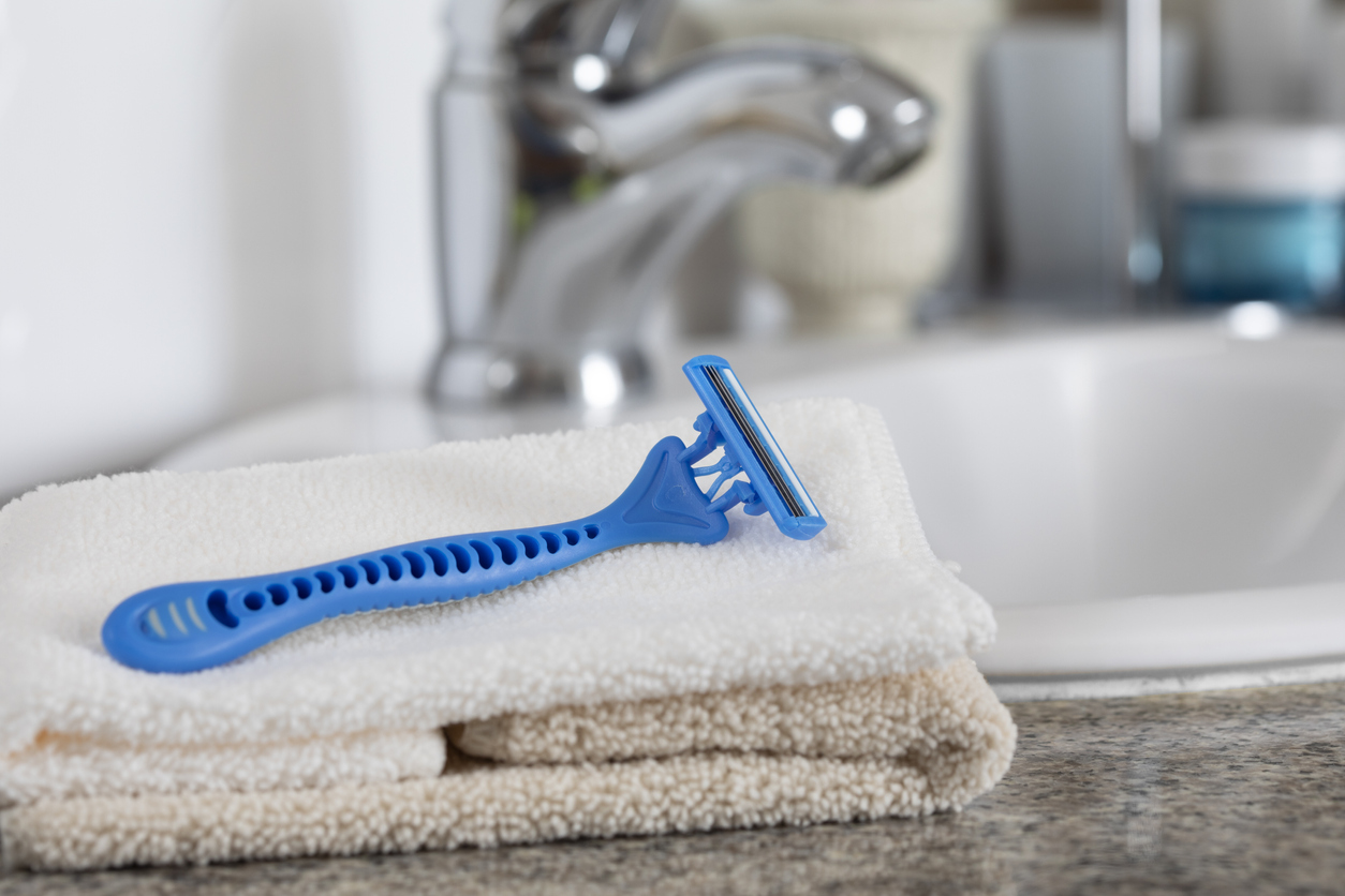 close view of razor blade on top of folded hand towel in bathroom next to sink