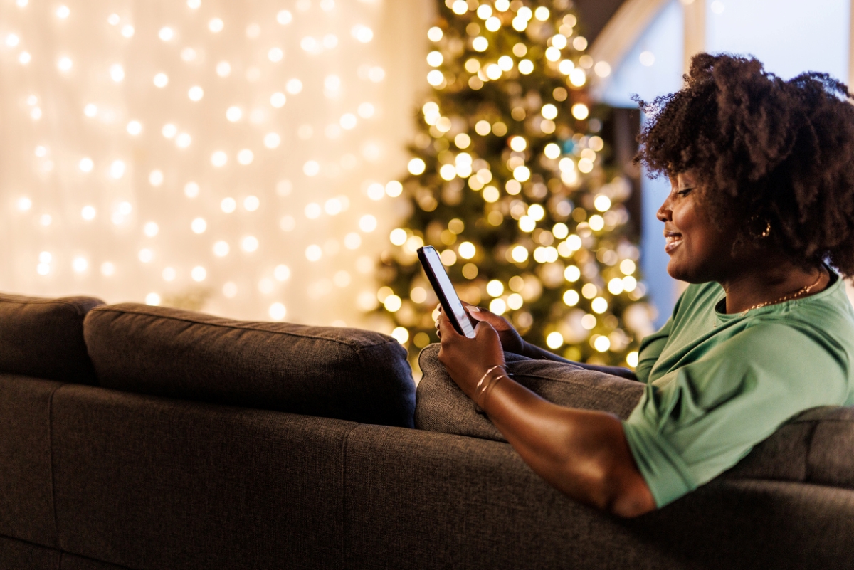 Woman using phone by holiday lights