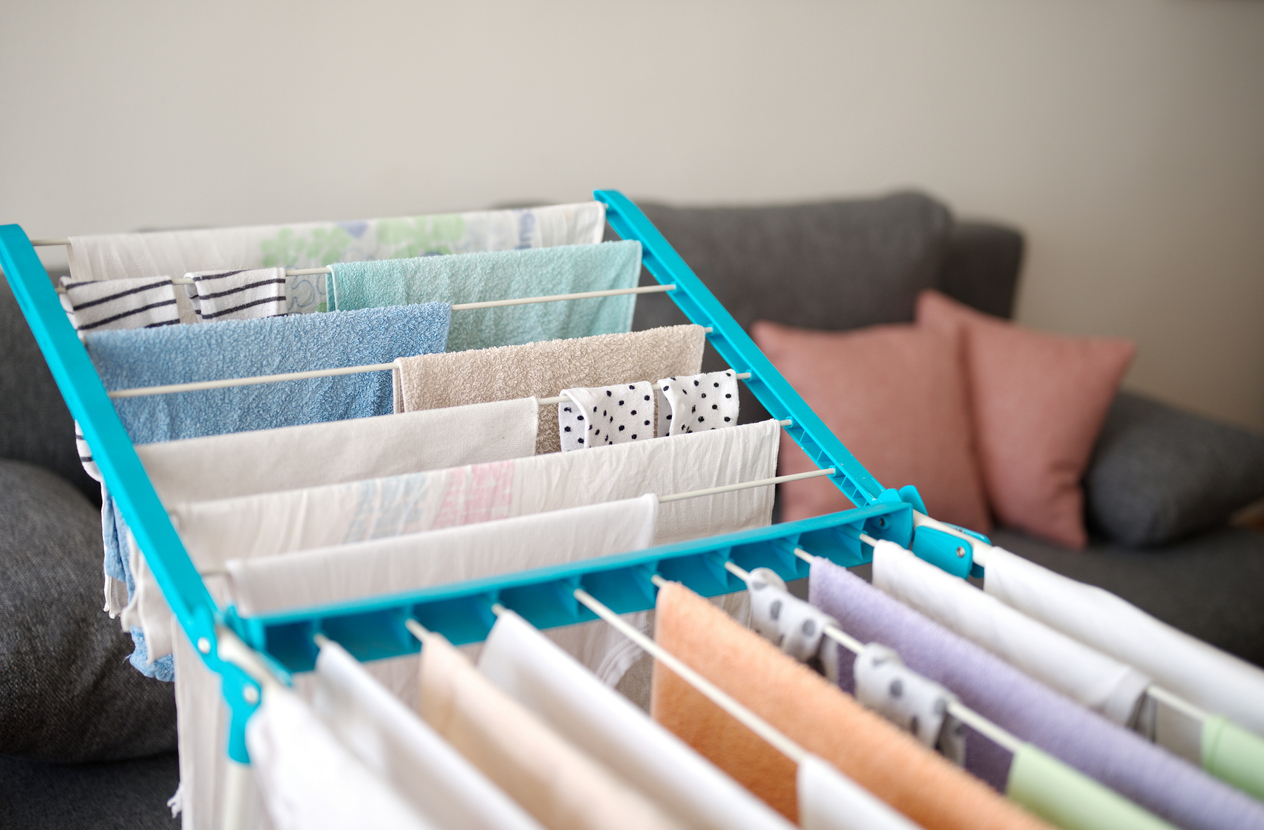 laundry drying on clothing rack in the living room with couch in the background