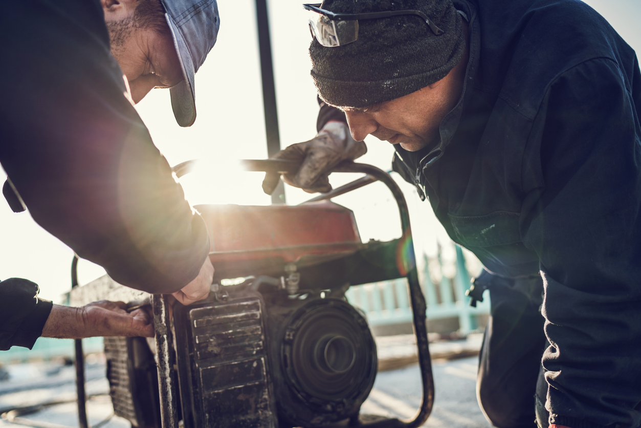 two men huddled over generator giving it a tune up