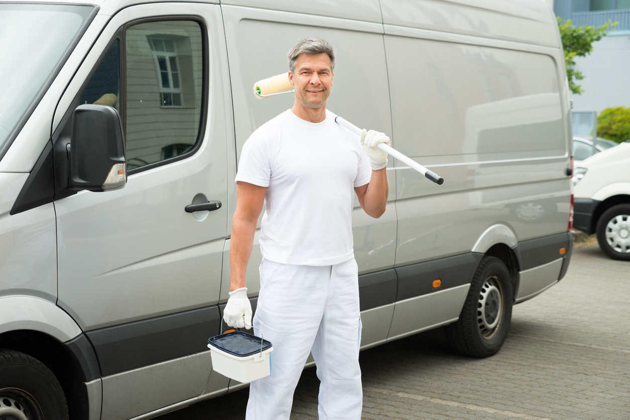 Happy Mature Painter Standing In Front Of Van