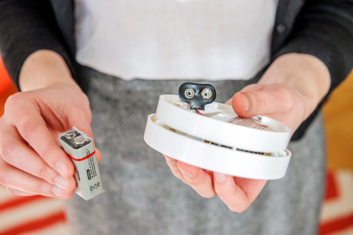 Woman putting battery in smoke alarm