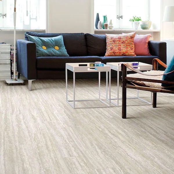 Light greige-colored vinyl flooring in a modern, airy living space with a navy couch and colorful pillows.