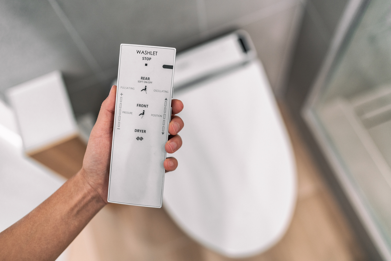 A person holding a remote over the best smart toilet option