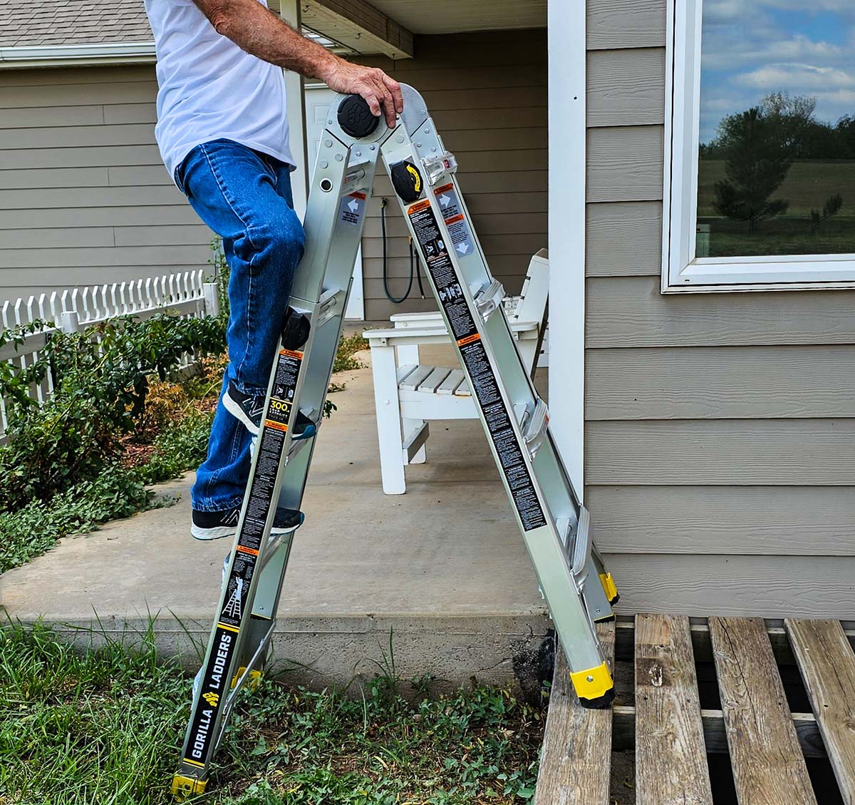 A person climbing the Gorilla ladder while it's set up in stairway position with one side on a pallet