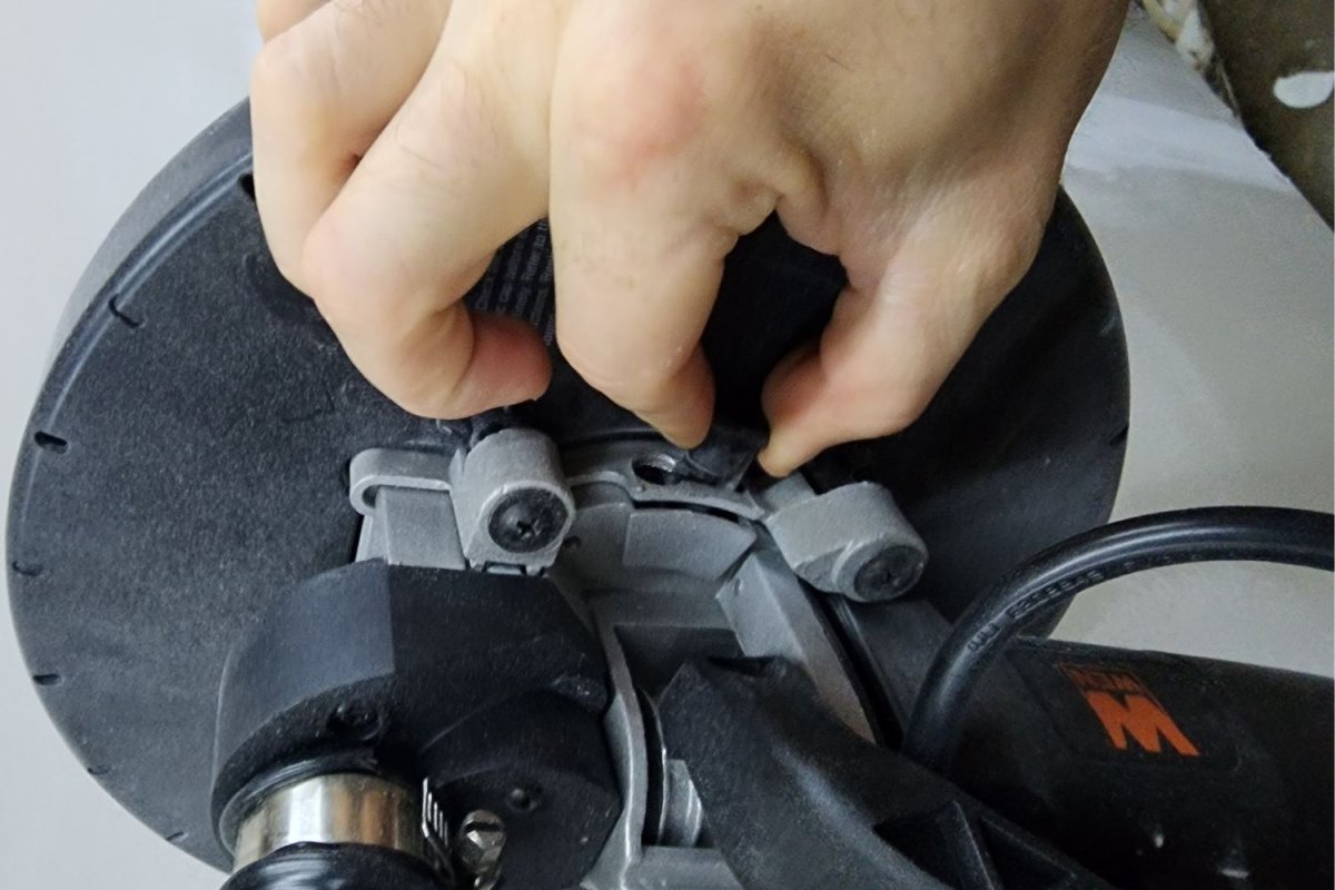 A close-up of a person making an adjustment on the Wen drywall sander