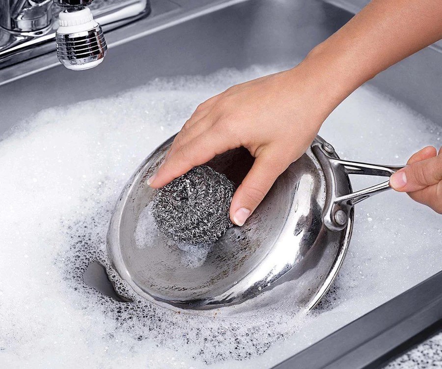 Person using steel wool pad to clean pan